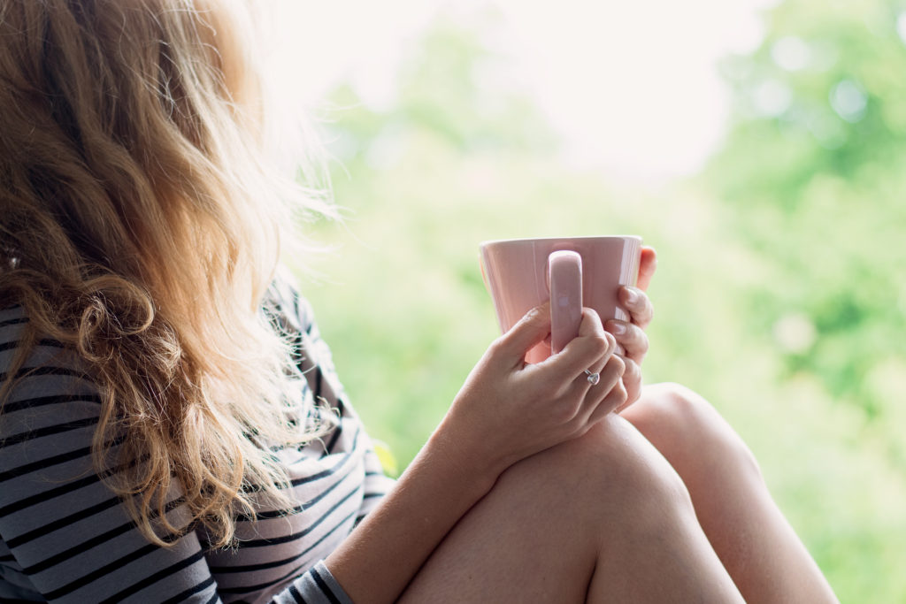 Find Your Inner Hygge With Image-Woman Holding A Pink Coffee Cup Looking Into the Distance